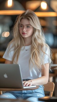 a woman sitting at a table with a laptop computer in her lap and looking off to the side