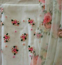 some pink flowers and green leaves on white fabric