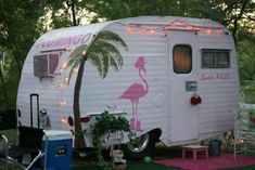 a pink flamingo camper parked next to a palm tree with lights on it