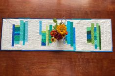 a quilted table runner with flowers in it on top of a wooden tablecloth