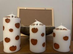 three white candles with pumpkins on them