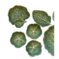 four green leaf shaped dishes on a white background