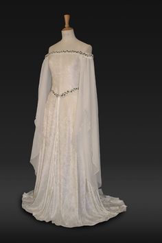 "Medieval Dress, Elvish Wedding Dress, Handfasting Dress, Elvish Gown,  Renaissance Gown, Medieval Gown, \"Guinevere\"  frockfollies is proud to add this beautiful new design to the collection. Guinevere is pure elegance in ivory crushed velvet with an elaborately embroidered off  the shoulder neckline and belt in an ivy design. It has a really romantic, elegant feel. The embroidery is in dark and light olive green. The long hanging sleeves are in ivory chiffon. The train can be made shorter at no extra cost. It is designed and custom made by Gill Linley of frockfollies. Perfect for so many occasions: Medieval, Renaissance, Elvish Weddings, Hand Fasting ceremonies, LARP events, Re Enactments, Masquerade Balls or your 'inner goddess' moments! Hand made in England by an experienced theatrica White Medieval Dress, Elvish Wedding Dress, Elvish Dress, Handfasting Dress, Elvish Wedding, Medieval Wedding Dress, Elven Dress, Medieval Gown, Medieval Wedding