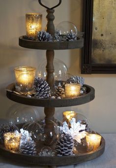 three tiered tray with candles and pine cones