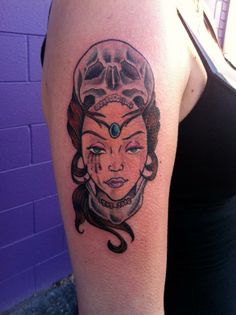 a woman's arm with a tattoo on it and a skull in the background