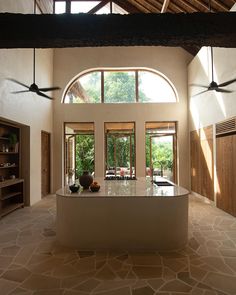 a large kitchen with an island in the middle and ceiling fans on either side of it