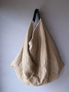 a beige bag hanging on the wall next to a white wall with a black handle