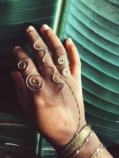 a woman's hand with rings and bracelets on her left wrist, against a green background