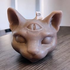 a ceramic cat's head on a table with a name tag attached to it