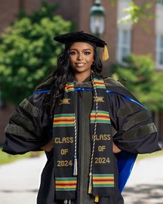 a woman wearing a graduation gown and holding her hands on her hip while standing in front of a building