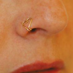 a woman's nose with a small heart shaped nose ring on it