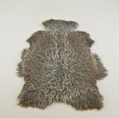 a sheepskin rug is laying on the floor in front of a white wall,