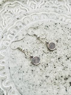 Experience the elegance of simplicity with these minimalist earrings featuring small silver swirls suspended from silver ear wires. Each pair captures the essence of contemporary chic and understated beauty. The delicate silver swirls add a touch of artistic flair to your everyday style, making them a versatile addition to your jewelry collection.  The spiral is a symbol of sacred geometry that represents continual growth, evolution, and transformation. It mirrors nature, from the unfolding of a fern frond to the galaxies spiraling in space. Spirals symbolize the journey from the center of being, expanding outward, and then returning to oneself, symbolizing both progress and a return to source. The spiral encourages us to embrace change, learn from our experiences, and strive for spiritual Nickel Free Silver Swirl Earrings, Minimalist Sterling Silver Swirl Earrings, Minimalist Silver Spiral Earrings, Minimalist Silver Swirl Earrings, Silver Swirl Earrings, Minimalist Spiral Nickel-free Earrings, Nickel-free Spiral Minimalist Earrings, Minimalist Swirl Earrings As Gift, Minimalist Swirl Earrings Gift