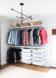 an organized closet with clothes and baskets on the bottom shelf, hanging from a chandelier