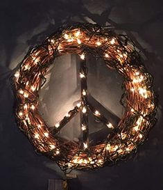 a peace sign is lit up with lights in the shape of a wreath on top of a table