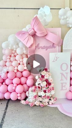 pink and white balloons are on display in front of a sign that says it's one