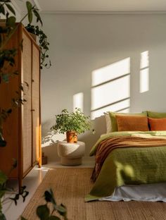 a bedroom with green bedding and plants in the corner