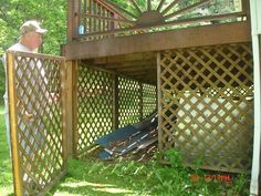 an old man standing in the back yard next to a wooden structure with lattice design on it