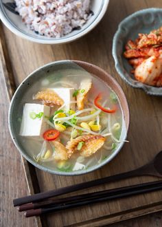 two bowls filled with food next to chopsticks on top of a wooden table