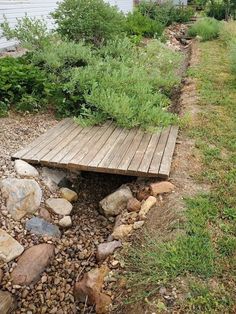 a wooden bench sitting on top of a pile of rocks next to a lush green field