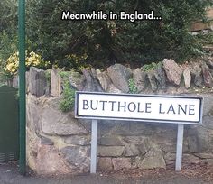 a sign that is in front of a stone wall and some trees on the other side