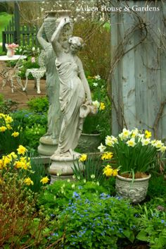 a statue in the middle of a garden surrounded by flowers and plants with text overlay