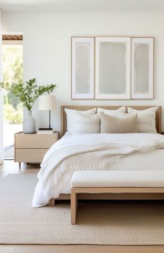 a bedroom with white bedding and two framed pictures on the wall above the bed