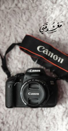 a canon camera sitting on top of a white carpet next to a black case with the word canon written in arabic