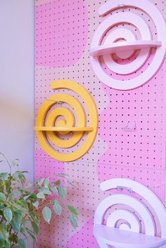 three different colored chairs sitting next to each other on a pink and white wall with holes in it