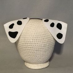 a white vase with black polka dots on it's sides and a head made out of yarn