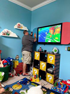 a man standing in front of a tv playing mario kart on the nintendo wii