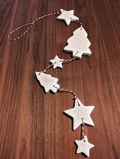 three white ceramic stars hanging from string on wooden table with wood grained surface in the background