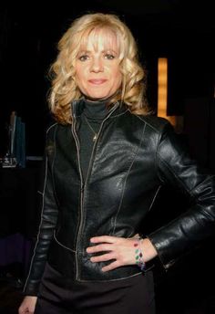 a woman in a black leather jacket posing for the camera with her hands on her hips