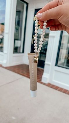 a hand holding a tube of toothpaste with pearls hanging from it's end