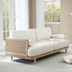 a white couch sitting in front of a window on top of a carpeted floor