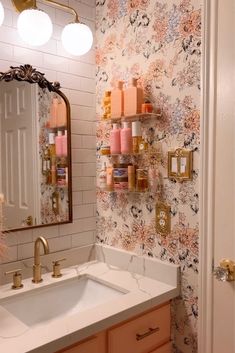 a bathroom sink sitting under a mirror next to a shelf filled with bottles and candles