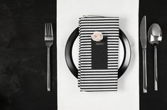 a black and white place setting with silverware, napkins and utensils