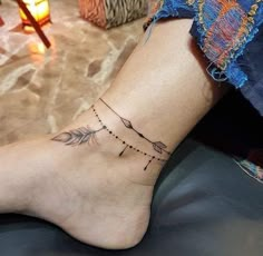 a woman's foot with an arrow tattoo on her left ankle and a candle in the background