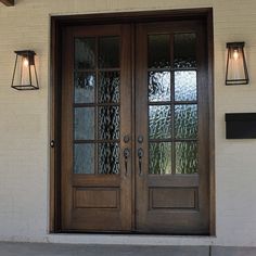 the front door to a house with two lights on each side