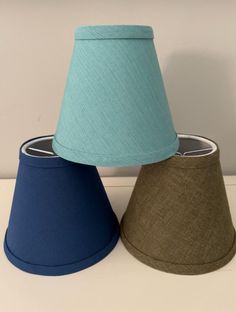 two lamps sitting next to each other on top of a white table with a blue lamp shade