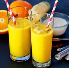 two glasses filled with orange juice next to an orange slice