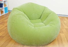 a green bean bag chair sitting on top of a hard wood floor next to a book shelf