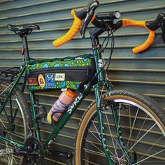 a green bicycle parked next to a garage door with orange handles and socks on the handlebars