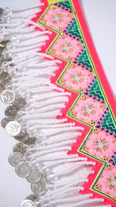 some coins are laying next to each other on a white tablecloth with red and green border