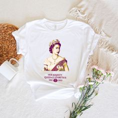 a t - shirt with an image of the queen on it next to some flowers