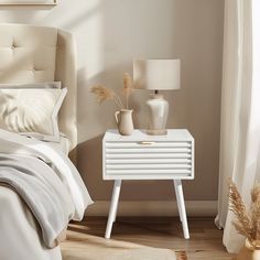 a white nightstand sitting next to a bed in a bedroom