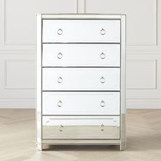 a white chest of drawers sitting on top of a hard wood floor next to a wall