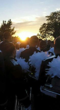 a group of people sitting next to each other in front of the sun with white feathers