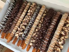 a box filled with lots of different types of donuts and pretzel sticks