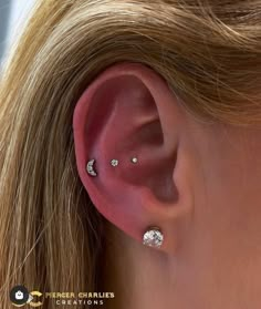 a close up of a person's ear with three piercings